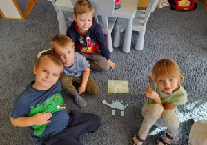 Grupa dzieci prezentuje ułożonego wg wzoru dinozaura.